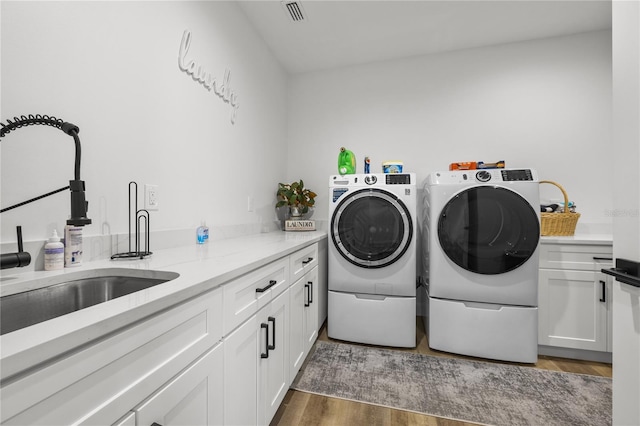 washroom featuring cabinets, wood-type flooring, sink, and washing machine and clothes dryer