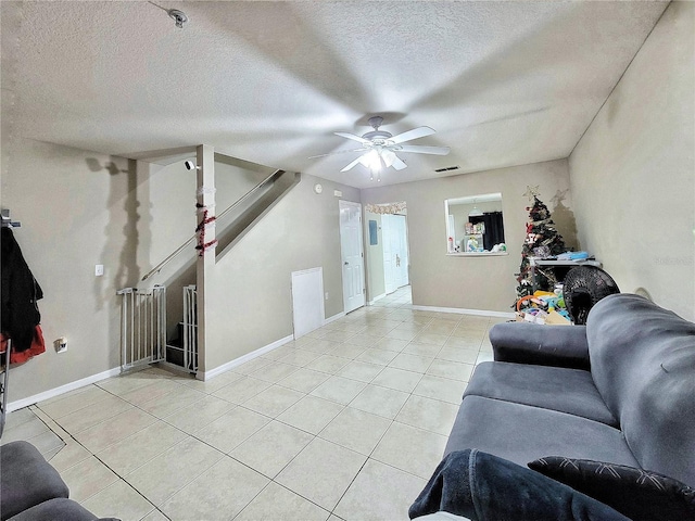 living room featuring light tile patterned flooring, ceiling fan, and a textured ceiling