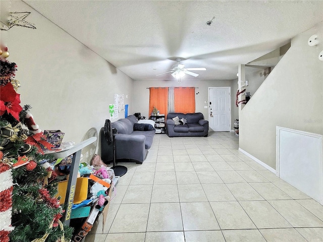 living room with ceiling fan, a textured ceiling, and light tile patterned floors