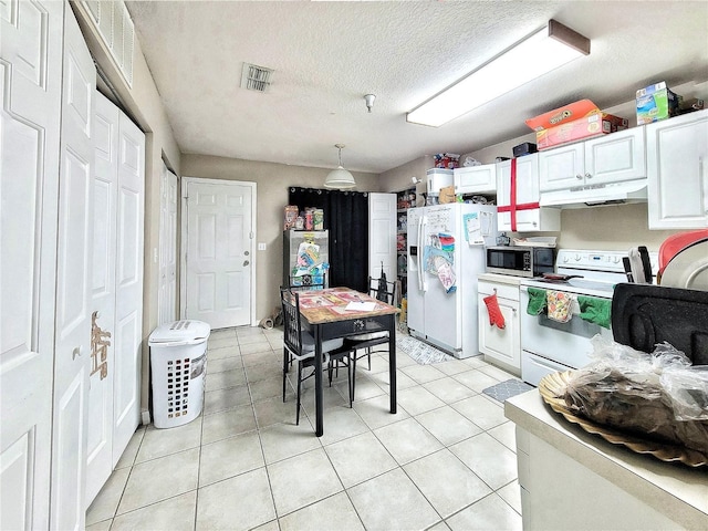 kitchen featuring white appliances, light tile patterned floors, hanging light fixtures, and white cabinets