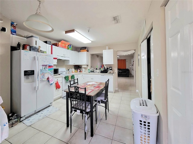 kitchen with light tile patterned flooring, white cabinets, white appliances, and decorative light fixtures