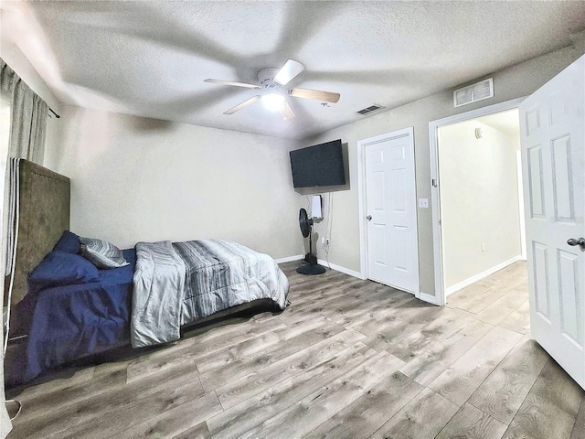 bedroom with ceiling fan, a textured ceiling, and light wood-type flooring