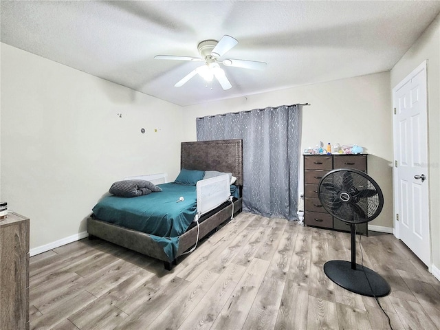 bedroom featuring ceiling fan, light hardwood / wood-style flooring, and a textured ceiling