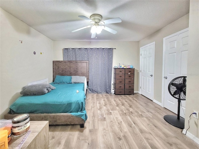 bedroom featuring ceiling fan, light hardwood / wood-style floors, and a textured ceiling