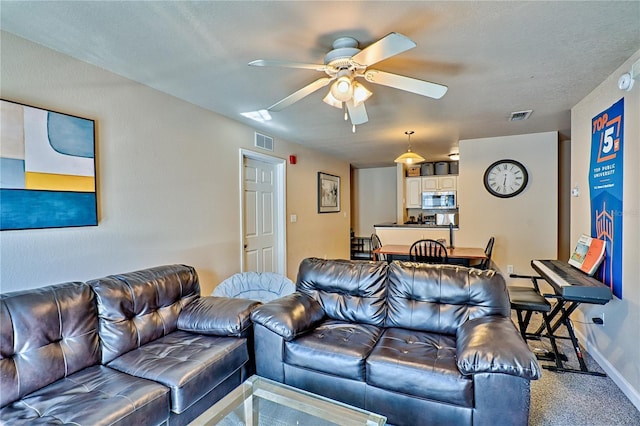 carpeted living room featuring a textured ceiling and ceiling fan