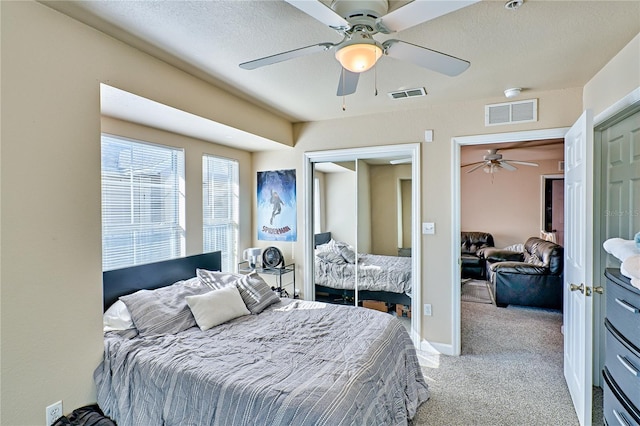 carpeted bedroom featuring ceiling fan and a textured ceiling