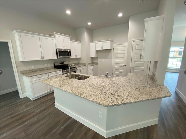 kitchen with stainless steel appliances, light stone countertops, dark wood-type flooring, white cabinets, and sink