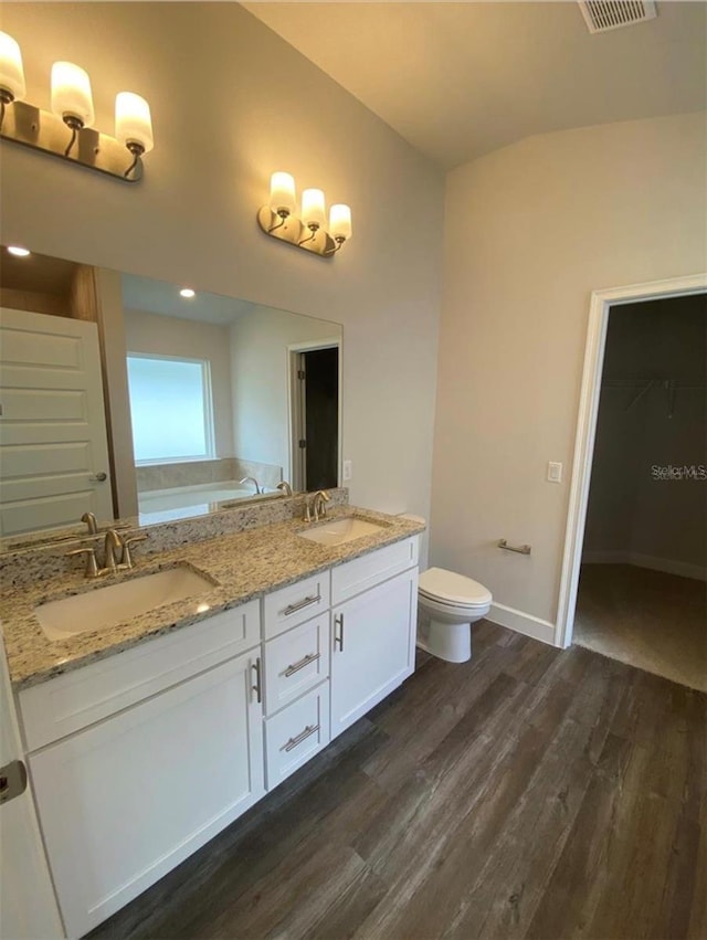 bathroom with toilet, lofted ceiling, wood-type flooring, and vanity