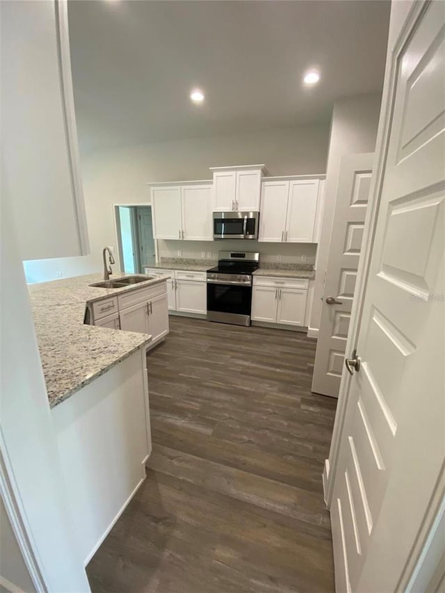 kitchen featuring light stone counters, kitchen peninsula, stainless steel appliances, white cabinetry, and sink