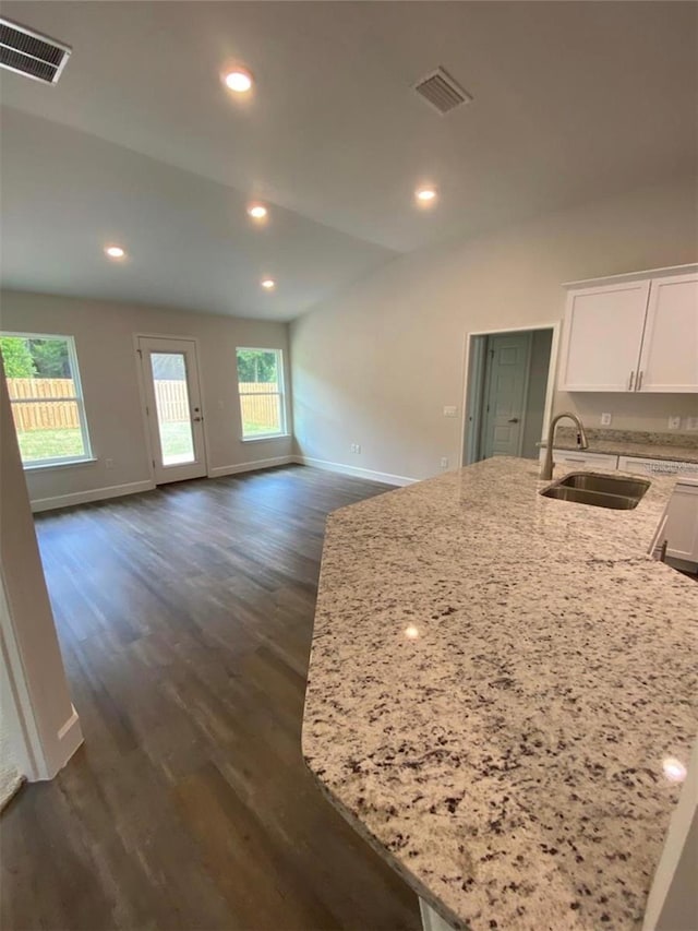 kitchen with sink, white cabinets, an island with sink, light stone countertops, and dark hardwood / wood-style flooring