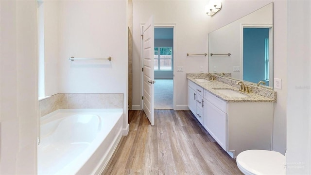 bathroom featuring a bath, hardwood / wood-style floors, vanity, and toilet