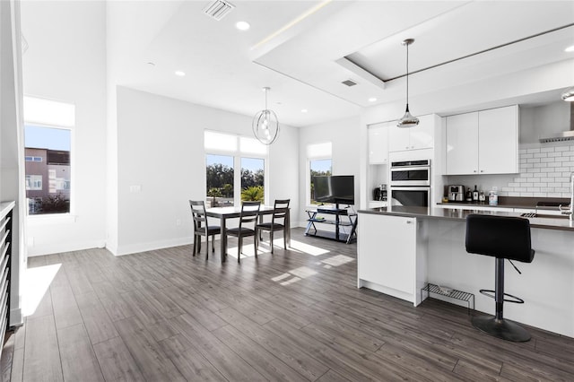 kitchen with double oven, white cabinetry, dark hardwood / wood-style flooring, and hanging light fixtures