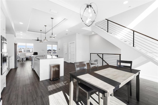 dining space with dark hardwood / wood-style flooring, a raised ceiling, ceiling fan, and sink