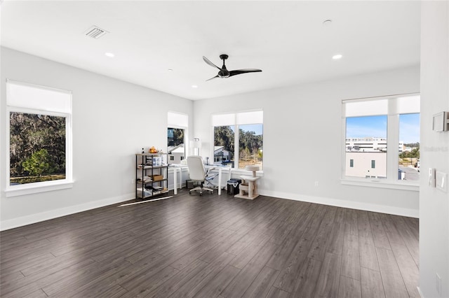 unfurnished office featuring plenty of natural light, ceiling fan, and dark wood-type flooring