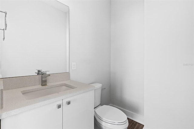 bathroom with hardwood / wood-style floors, vanity, and toilet