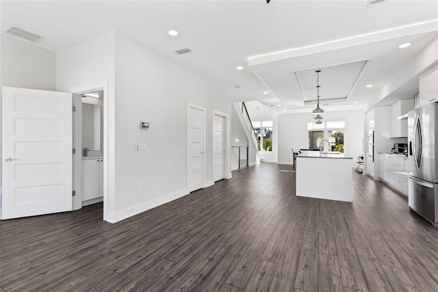 kitchen featuring hanging light fixtures, stainless steel fridge, a tray ceiling, dark hardwood / wood-style flooring, and white cabinetry