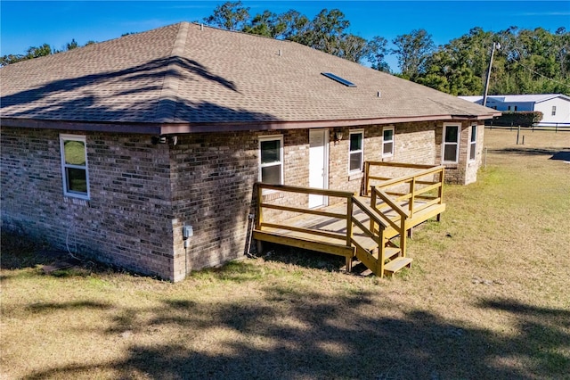 rear view of house with a deck and a lawn