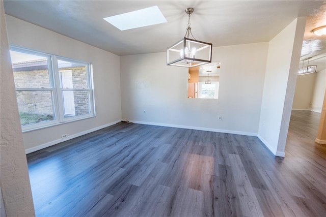 unfurnished dining area with an inviting chandelier, dark wood-type flooring, a wealth of natural light, and a skylight