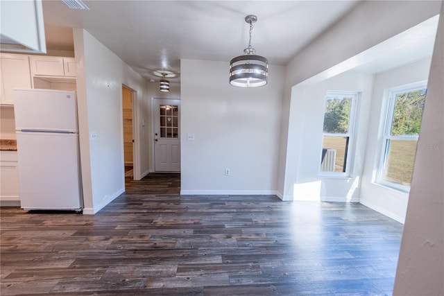 unfurnished dining area featuring dark hardwood / wood-style floors and an inviting chandelier