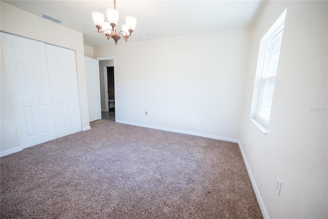 unfurnished bedroom featuring carpet, a notable chandelier, and a closet