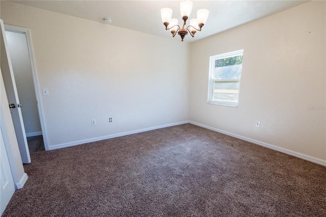 empty room with dark carpet and a notable chandelier