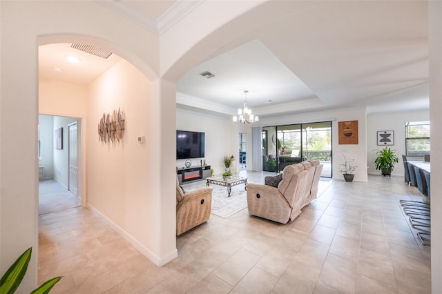 living room with a raised ceiling, an inviting chandelier, light tile patterned floors, and crown molding