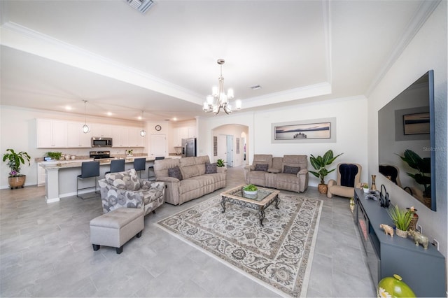 living room featuring an inviting chandelier, a tray ceiling, and crown molding