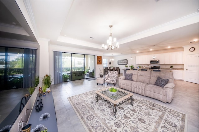 living room featuring light tile patterned flooring, a chandelier, a tray ceiling, and ornamental molding