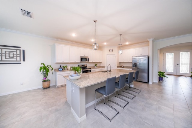 kitchen featuring appliances with stainless steel finishes, an island with sink, french doors, and white cabinetry