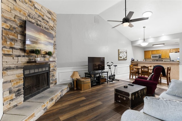 living room featuring dark hardwood / wood-style flooring, a fireplace, ceiling fan, and vaulted ceiling