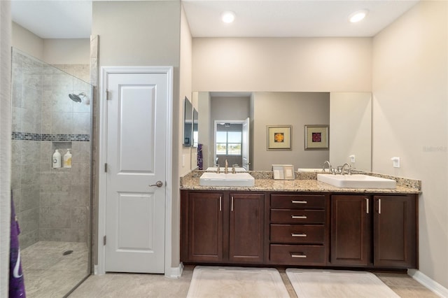 bathroom with vanity, a tile shower, and tile patterned flooring