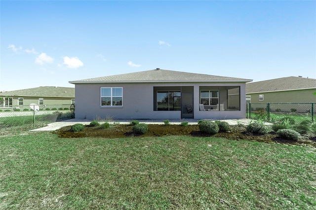 rear view of house featuring a sunroom and a lawn