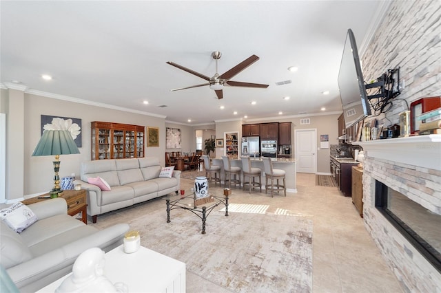 tiled living room featuring ceiling fan, ornamental molding, and a fireplace