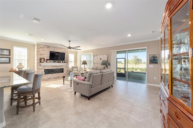 living room featuring ceiling fan, light tile patterned floors, ornamental molding, and a stone fireplace