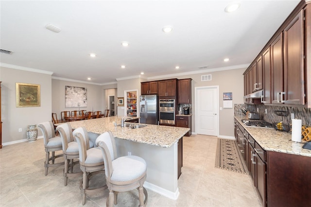 kitchen featuring light stone countertops, appliances with stainless steel finishes, sink, and a center island with sink