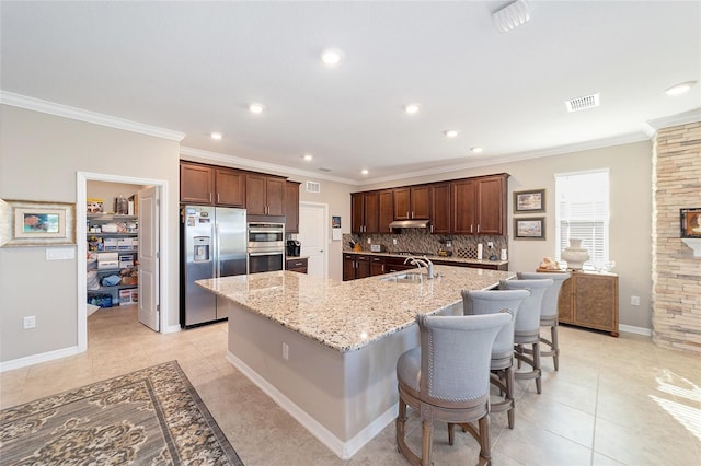 kitchen featuring a spacious island, a kitchen bar, appliances with stainless steel finishes, ornamental molding, and light stone counters