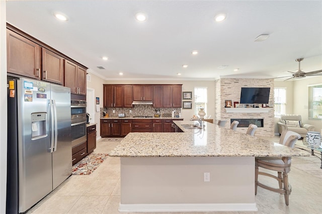 kitchen with appliances with stainless steel finishes, sink, a large island, crown molding, and a breakfast bar area