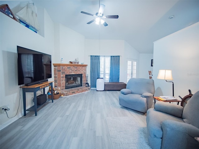 living room featuring high vaulted ceiling, light hardwood / wood-style floors, a brick fireplace, and ceiling fan