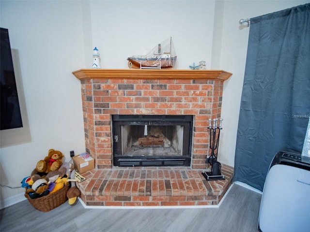 interior details featuring wood-type flooring and a brick fireplace