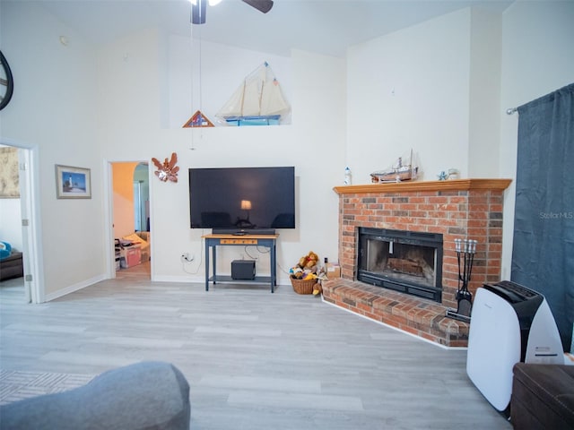 living room with ceiling fan, hardwood / wood-style floors, and a brick fireplace