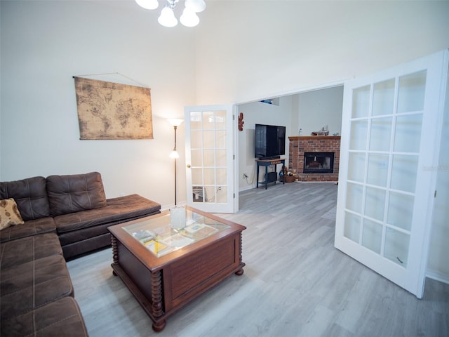 living room featuring hardwood / wood-style floors, a chandelier, and a brick fireplace