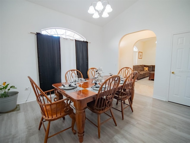 dining room with lofted ceiling, a notable chandelier, and light wood-type flooring