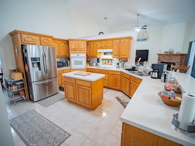 kitchen with white oven, ceiling fan, stainless steel fridge, cooktop, and kitchen peninsula