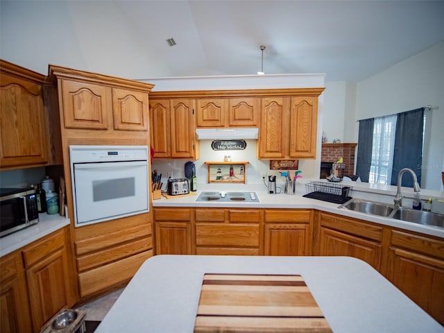 kitchen featuring white appliances, vaulted ceiling, and sink