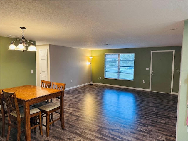 dining area with dark wood-type flooring, a textured ceiling, and a notable chandelier