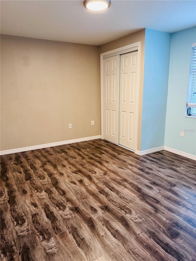 unfurnished bedroom with a closet and dark hardwood / wood-style flooring