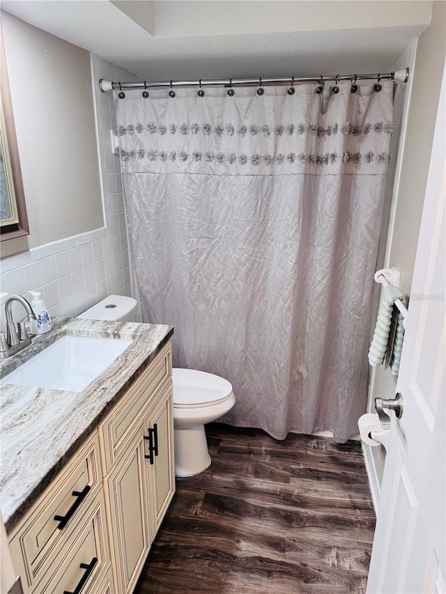 bathroom with vanity, toilet, tile walls, curtained shower, and wood-type flooring