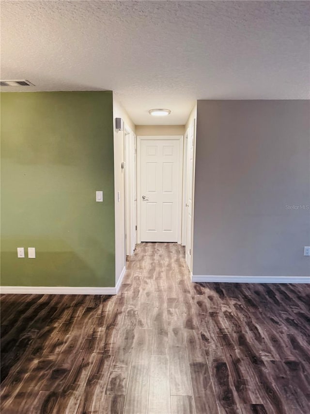 hallway with wood-type flooring and a textured ceiling