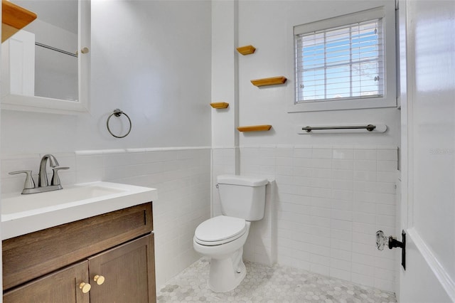 bathroom featuring tile patterned floors, vanity, tile walls, and toilet