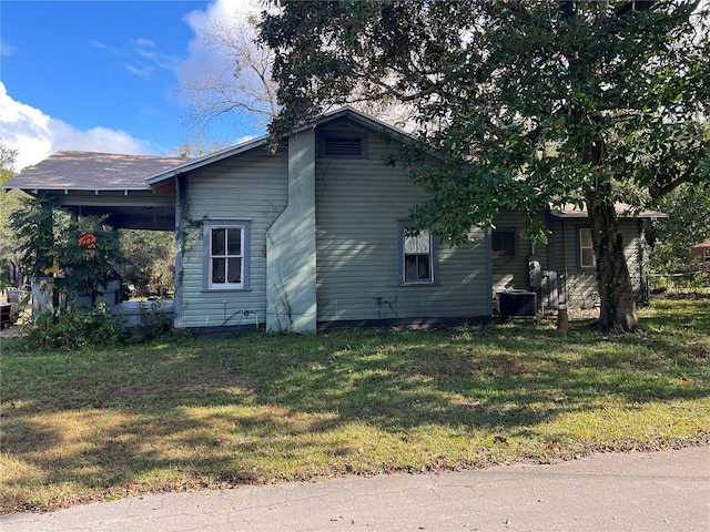 view of side of property featuring central AC unit and a yard